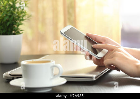 Close up Portrait of a Lady Hände berühren ein Smartphone in einem Hause Raum über eine Tabelle mit einem Fenster im Hintergrund Stockfoto