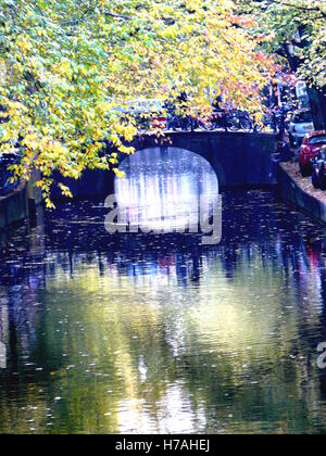 Brücke und Bäume auf noch Wasser auf einer Amsterdamer Gracht im Herbst reflektiert. Perfekte Aufnahme für Reiseberichte, ADS und Marketing Abenteuer Produkte Stockfoto