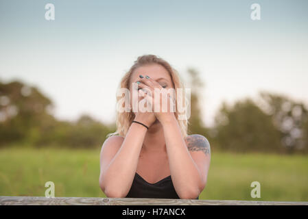 Blonde Frau für Gesicht mit den Händen. Konzept - peinlich, lachen oder überrascht Stockfoto