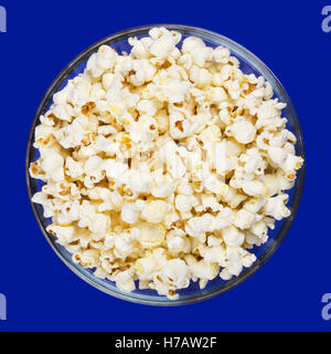 Popcorn in Glasschüssel auf blauem Hintergrund. Schmetterling-förmige tauchte Popcorn aus der Maiskörner aufgeblasen. Stockfoto