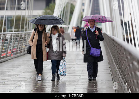 London, UK. 4. November 2016. Touristen-Schutz vor dem Regen mit Sonnenschirmen auf Golden Jubilee Bridge in Westminster, London heute Nachmittag. Bildnachweis: London Pix/Alamy Live News Stockfoto