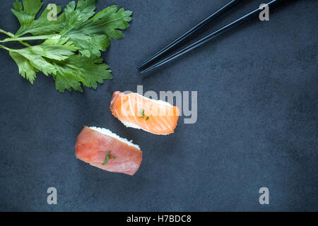 Nahansicht des frischen Thunfisch und Lachs Nigiri und Stäbchen auf eine dunkle Platte Stockfoto
