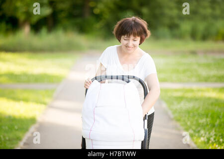 Großmutter mit dem Kinderwagen im Park spazieren Stockfoto