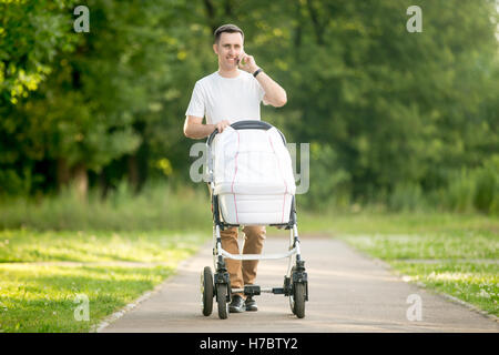 Mann, die Kinderwagen schieben und telefonieren im park Stockfoto