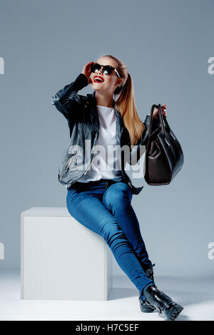 Mode-Modell auf weißen Würfel lächelnd in Sonnenbrillen Stockfoto