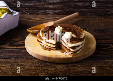 Hausgemachte Pfannkuchen warm mit Butter und Ahornsirup serviert auf rustikalen Holztisch Stockfoto