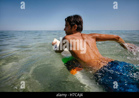 Schuss des Jünglings auf Surfbrett im Ozean treiben. Junger Mann, die einen Surfen im Wasser des Meeres zu genießen. Stockfoto