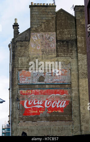 Alte Vintage-Werbeschilder auf der Seite des Mietshauses Koks Coca Cola Nachrichten der Welt und Bier Stockfoto