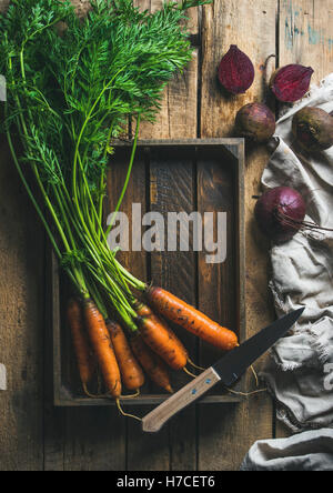 Gesundes Essen kochen Hintergrund. Pflanzliche Inhaltsstoffe. Garten frische Karotten und rote Beete in Holztablett über rustikale Holz bac Stockfoto