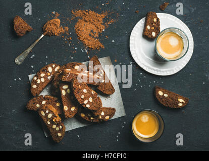 Dunkle Schokolade und Meersalz Biscotti mit Mandeln und zwei Gläser Kaffee Espresso über dunklem Stein, Draufsicht, selec Stockfoto