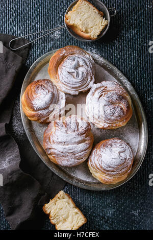 Moderne Gebäck Cruffins, ganzen und in Scheiben schneiden, wie Croissants und Muffins mit Puderzucker, serviert auf Vintage Metalltablett mit Sieb Stockfoto