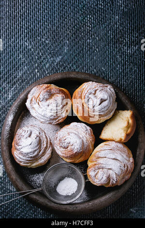 Moderne Gebäck Cruffins, ganzen und in Scheiben schneiden, wie Croissants und Muffins mit Puderzucker, serviert im Ton-Tray mit Vintage Sieb o Stockfoto