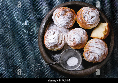 Moderne Gebäck Cruffins, ganzen und in Scheiben schneiden, wie Croissants und Muffins mit Puderzucker, serviert im Ton-Tray mit Vintage Sieb o Stockfoto