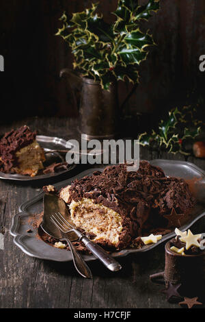 In Scheiben geschnitten hausgemachte Schokolade Yule Bûche mit Kastanien Creme auf Vintage Platte mit Gabeln, Schoko Stars und Holly branch Stockfoto