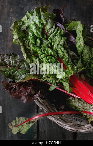 Frischen Mangold Salatblätter Mangold in alten Korb in dunklem Holz. Draufsicht mit Platz für Text. Gesunde Ernährung Thema. Stockfoto