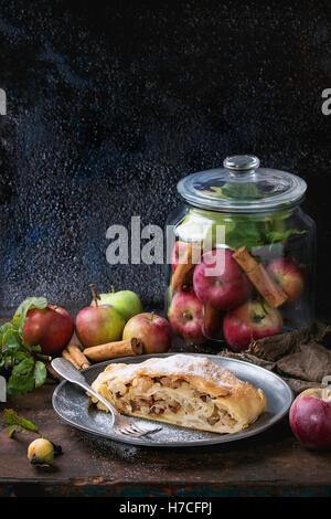 In Scheiben geschnitten serviert mit frischen Äpfeln im Glas hausgemachten Apfelstrudel, Zimtstangen und Puderzucker auf Vintage Metall Platte Witz Stockfoto