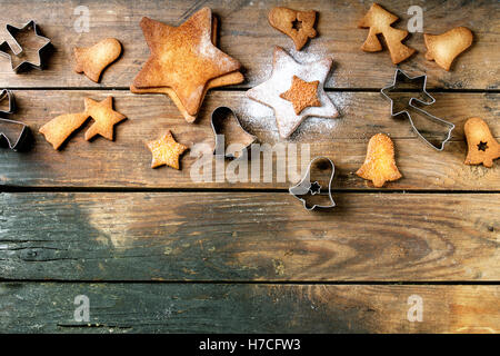 Hausgemachte Weihnachten Shortbread Sternform sugar Cookies unterschiedlicher Größe mit Zucker Pulver und Cookie Cutter auf alten Holzoberfläche Stockfoto