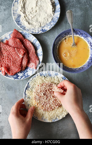 Hände, die Beschichtung Rindfleisch in Paniermehl. Zubereitung schnitzel Stockfoto