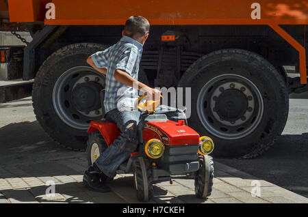 Ein Junge spielt mit einem Spielzeug-Traktor auf einer Straße in Istanbul. Stockfoto