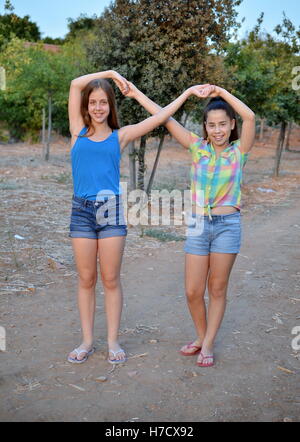 Beste Freunde für immer - zwei 12-jährige Mädchen Hand in Hand in eine Unendlichkeit ewig Zeichen zu bedeuten BFF Stockfoto