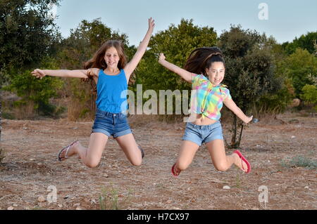 Beste Freunde für immer - zwei 12-jährige Mädchen im Teenageralter springen in der Luft eingefroren Stockfoto