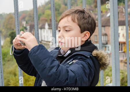 Ein kleiner Junge mit dem Fotografieren auf der Eisenbrücke am Ironbridge in Shropshire, England. Stockfoto