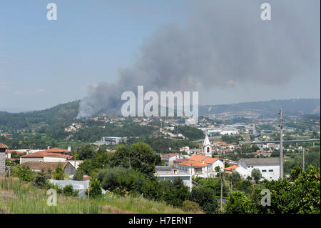 Rauchfahne aus einem Wald und Buschfeuer auf Hügel in der Nähe von Braga in Portugal Stockfoto