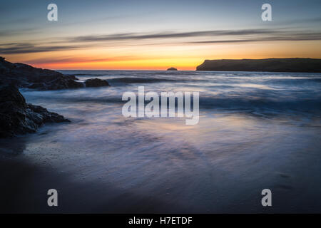 Nach dem Sonnenuntergang am Polzeath in Cornwall Großbritannien gegen Wasser mit langsamer Verschlusszeit Bewegungsunschärfe Wirkung verleihen Stockfoto