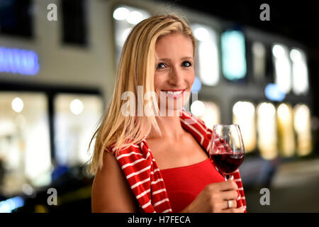 Frau mit einem Glas Wein in der Hand, auf der Straße, in der Nacht, Deutschland Stockfoto