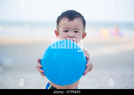Kleine asiatische junge 1 Jahr alt, Ballspiele am Strand in Thailand