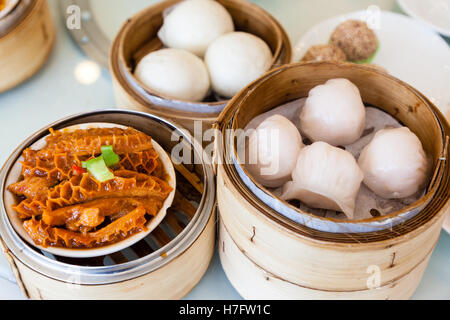 Gedämpfte chinesische Dim-Sum serviert im Bamboo Steamer, einschließlich Brötchen, geschmortem Rindfleisch Tripes und Garnelen Knödel. Stockfoto