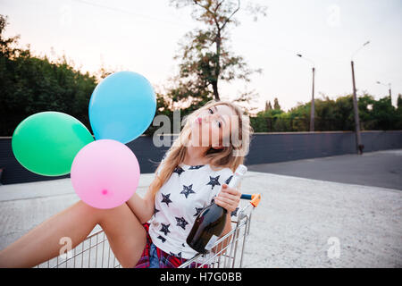 Porträt von glücklich lächelnde blonde Frau Spaß allein im Einkaufswagen Stockfoto