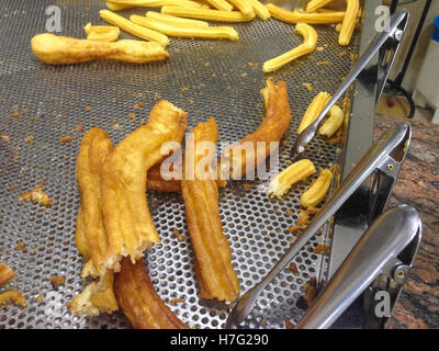 Spanischen Churros und Porras mit einer Zange servierbereit Stockfoto