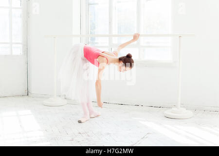 Ballerina posiert in Spitzenschuhen am weißen Holzpavillon Stockfoto