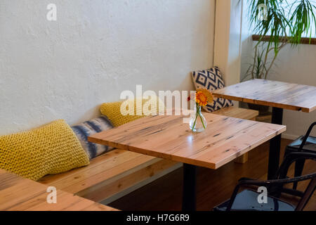 Sitzbank in einem Café-Restaurant mit kleinen Café-Tischen und Kissen. Stockfoto