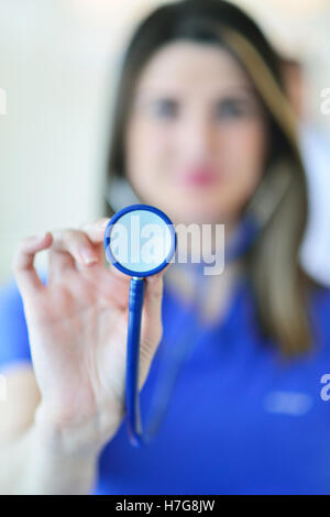 Frau Doktor lächelnd und auf der Suche auf die Kamera, während ein Ärzteteam arbeitet Stockfoto