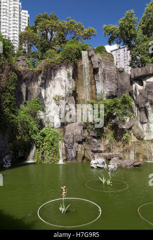 Blick auf einen Teich, Klippe und künstlichen Wasserfall bei der Sik Sik Yuen Wong Tai Sin Temple in Hong Kong, China. Stockfoto