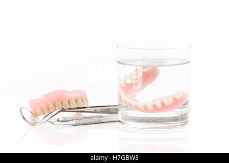 Nahaufnahme von Zahnersatz in Glas Wasser und dental Werkzeug, Mundspiegel auf weißen backgrounda Stockfoto