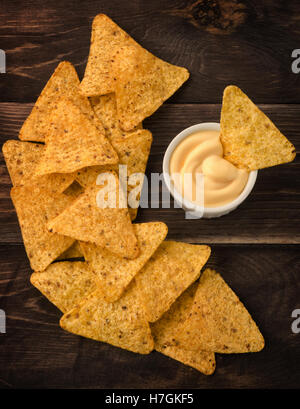 Nachos mit Käse-Dip auf einem Holztisch, Ansicht von oben Stockfoto