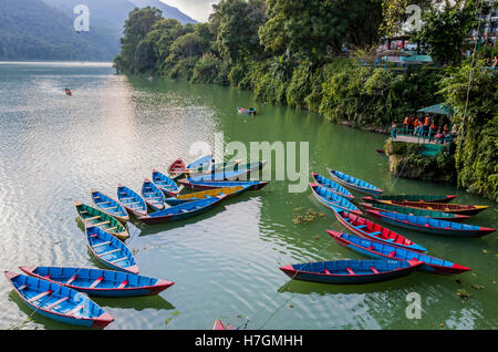 Menschen, die ein Boot rudern, während andere Ruderboote Kunden auf See Fewa Pokhara Kathmandu warten. Stockfoto