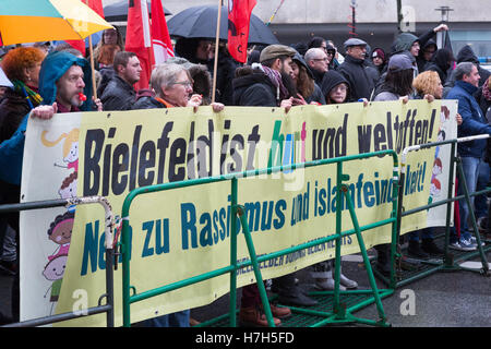 Die Demonstranten in eine linke Kundgebung in Bielefeld, Deutschland vor einem Schild, dass die Stadt geöffnet ist und multi-ethnischen. Stockfoto