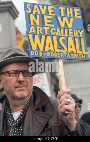 London, UK. 5. November 2016. Bob & Roberta Smith hält einen kleinen gemalten Plakat Unterstützung der New Art Gallery in Walsall gegen Schließung plant n auf den Stufen auf dem Trafalgar Square am Ende des Marsches von mehr als zweitausend Menschen aus der British Library zur Unterstützung der öffentlichen Bibliotheken, Museen und Kunstgalerien, bedroht durch die Regierung Kürzungen und Verschlüsse als lokale Behörde, dass Budgets gekürzt werden. Im Vereinigten Königreich seit 2010 8.000 Bibliothek bezahlte und ausgebildete Arbeitnehmer ihren Arbeitsplatz verloren haben, 343 Bibliotheken wurden geschlossen (und anderen rund 300 Freiwilligen übergeben); und einer von fünf regionalen Museen sind Stockfoto