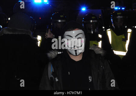 London, UK, 5. November 2016. Ein maskierter Demonstrant bei der Million Maske Protest trotzt eine Polizei Zerstreuung Reihenfolge. Tausende versammelten sich auf dem Londoner Trafalgar Square, Protest gegen Sparmaßnahmen, Stellenabbau und Umweltverschmutzung. Stockfoto