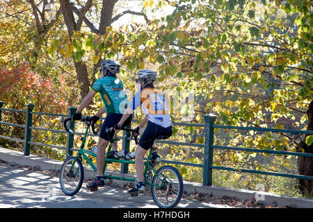 Behelmter Mann und Frau mit dem kleinen Rädern Tandem Fahrrad durch Minnehaha Park. Minneapolis Minnesota MN USA Stockfoto