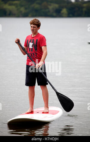 Teenager auf ein Stand up Paddle Board Paddeln auf einem See. Clitherall Minnesota MN USA Stockfoto