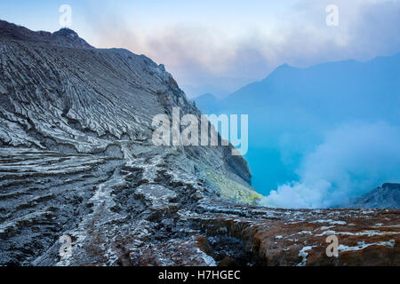 Sonnenaufgang Blick über Kawah Ijen mit dem blauen Schwefelsäure See am unteren Rand des Kraters. Java, Indonesien. Stockfoto