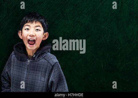 Intelligente Asian Boy mit im Klassenzimmer mit Tafel Hintergrund und Kopie Stockfoto