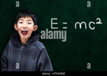 Intelligente Asian Boy mit im Klassenzimmer mit mathematische Gleichung auf Tafel Hintergrund und Kopie Raum Stockfoto