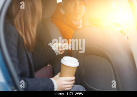 Bargeld für Durchgang Treiber sendet Brünette sitzt im taxi Stockfoto