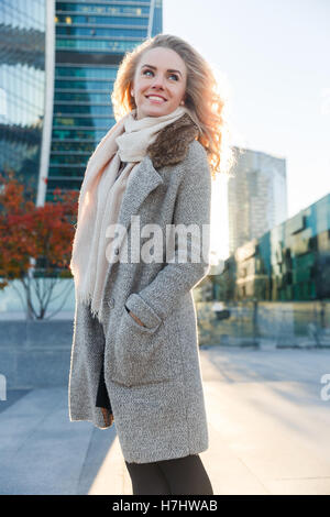 Glücklich Blondine im Mantel draußen Gebäude unter Herbst Stockfoto